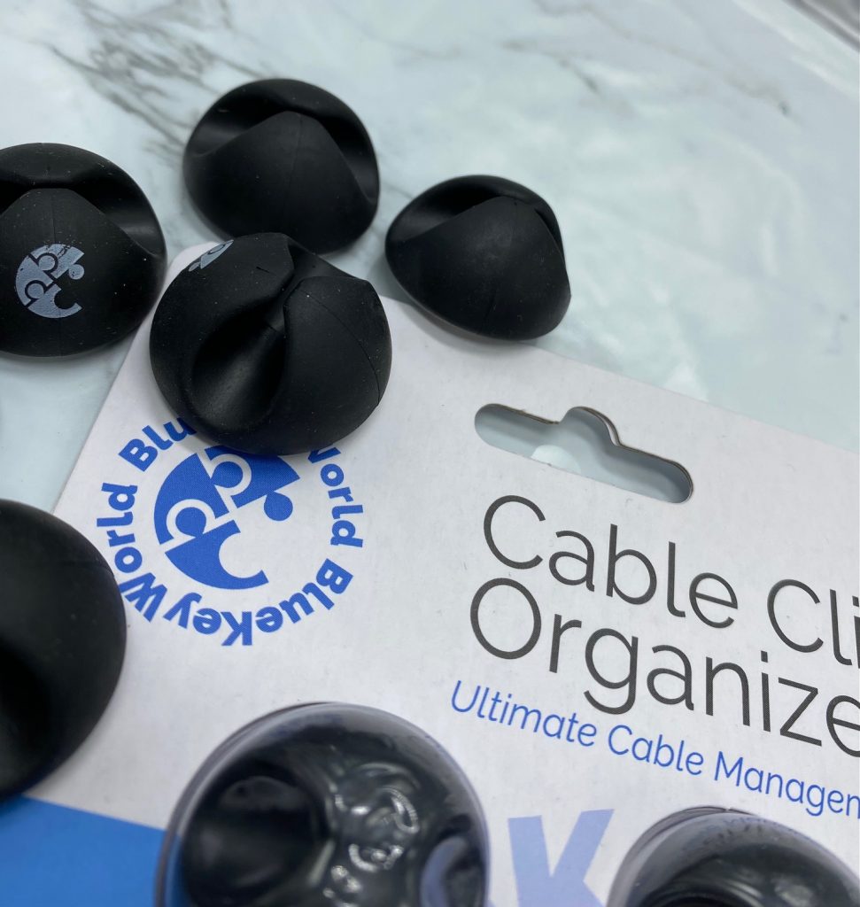 close up view of black wire holders laying on white package for bluekey world cable clip organizers