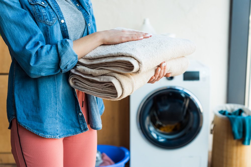 dryer sheet alternatives image of woman holding towels by washing machine