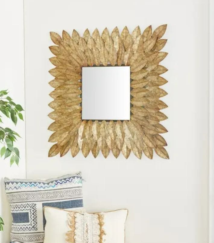 gold leaf mirror on white wall above pillows