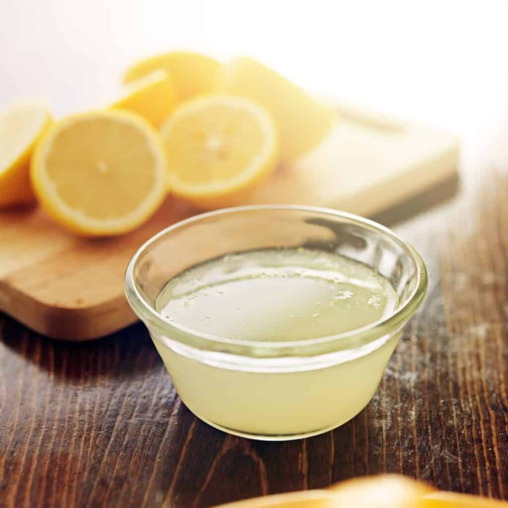 sliced lemons and bowl of lemon juice for how to clean shower head without vinegar