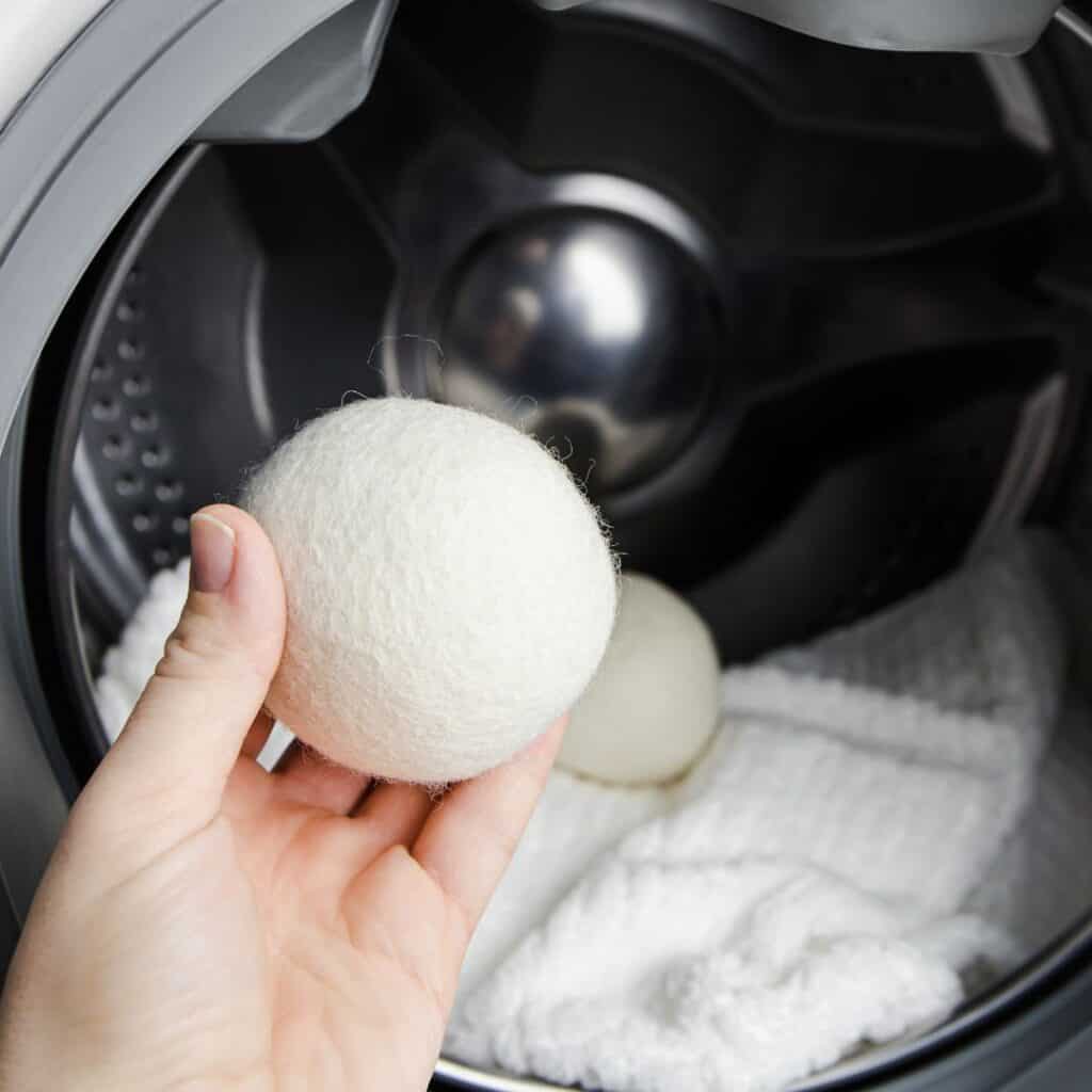 womans hand placing wool dryer ball into dryer