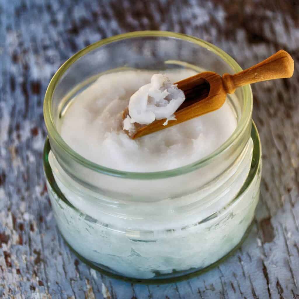 jar of coconut oil with a wooden paddle