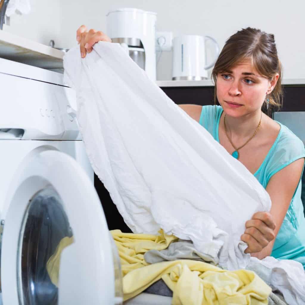 woman pulling white sheet out of dryer