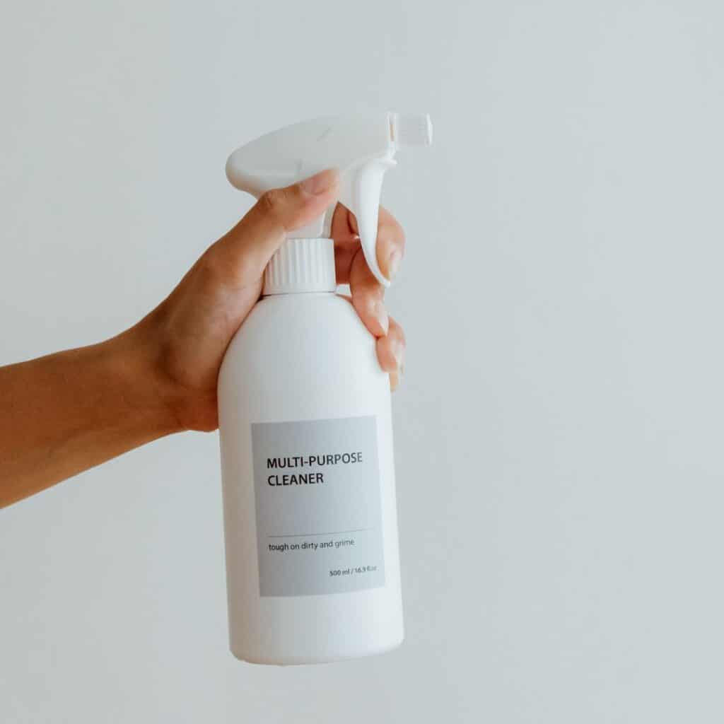 hand holding white spray bottle with gray label